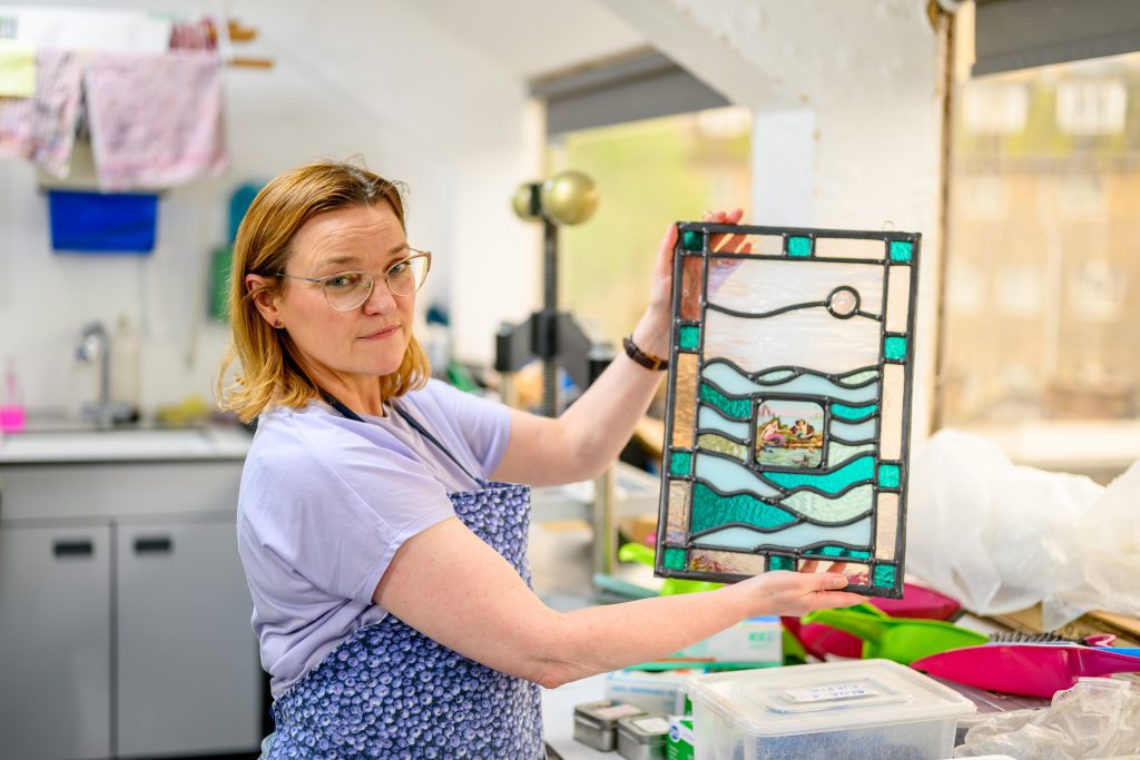 Women holding up glass artwork