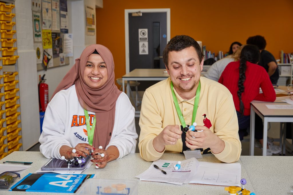 Women in headscarf next to male student in science lab