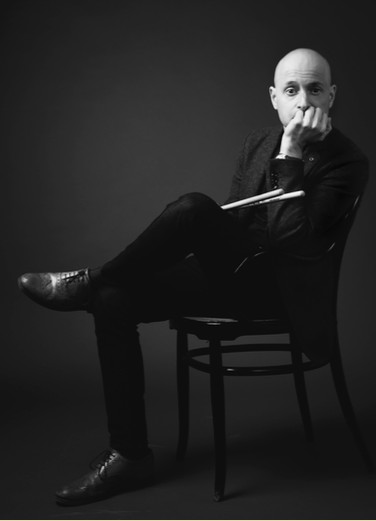 Black and white image of jazz tutor and Programme Area Manager Flavio Li Vigni, seated on a chair looking at the camera