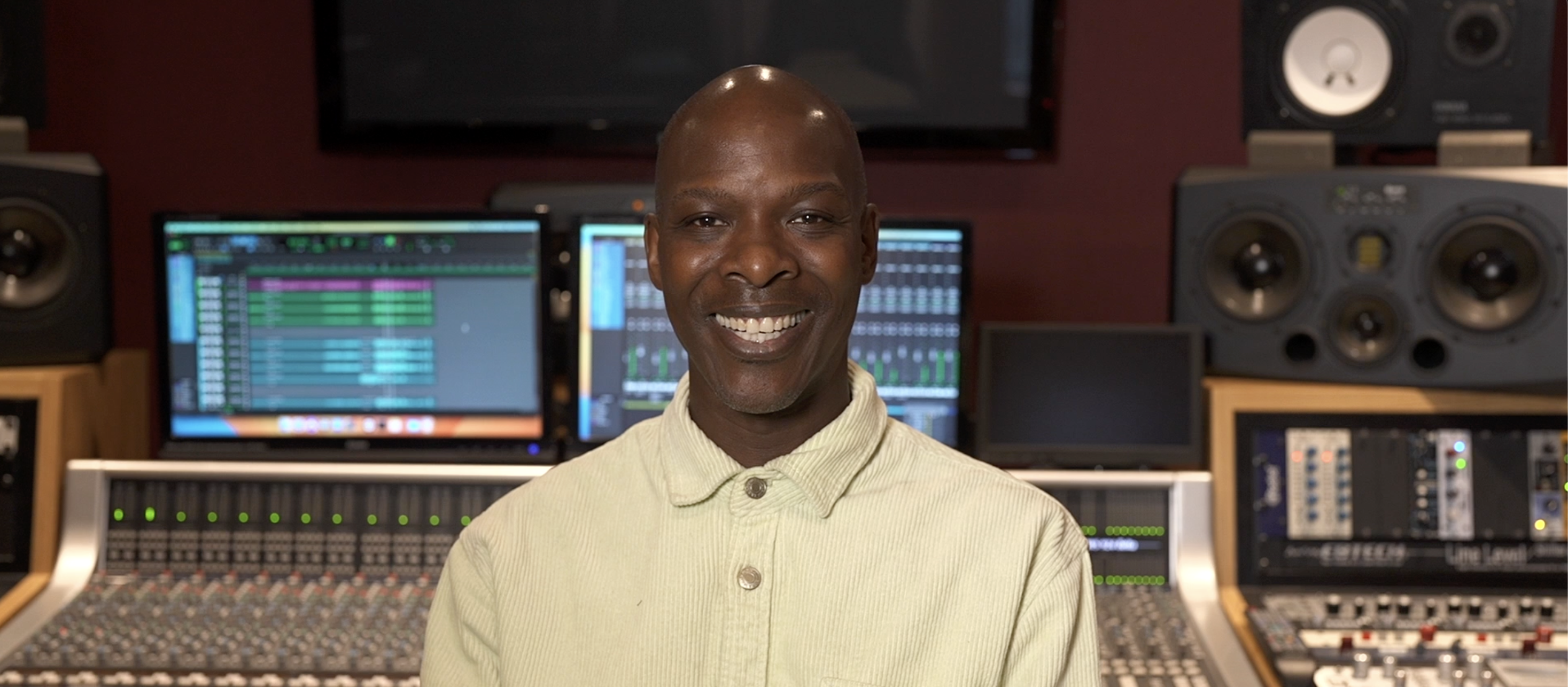 Black music technology tutor smiling in music studio